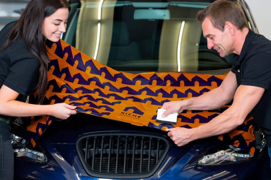 Car wrappers using squeegee to straighten vinyl foil