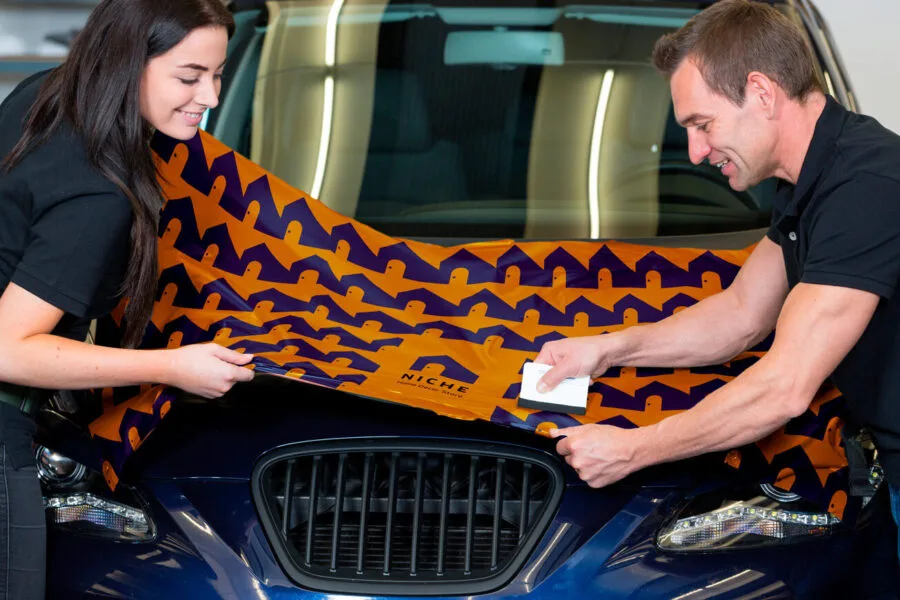 Car wrappers using squeegee to straighten vinyl foil